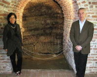 Giovanna Rizzolio and Italo Sobrino (proprietors) at the cut-out in their cellar that shows the striations of their terroir.